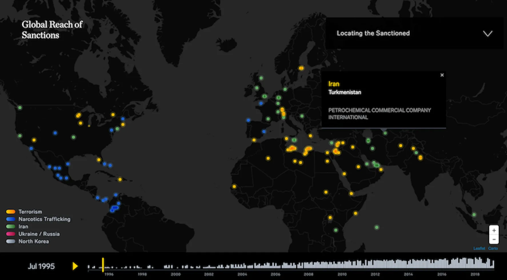 An image of a black and dark grey map of the world with brightly colored blue, green, and yellow dots on the countries that correlate to the global reach of sanctions. The key on the map covers color coding for Terrorism, Narcotics Trafficking, Iran, Ukraine / Russia, North Korea.